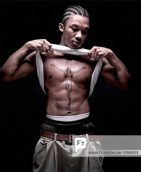 Junger Mann mit Tattoo Christi auf der Brust. . Lizenzpflichtiges Bild